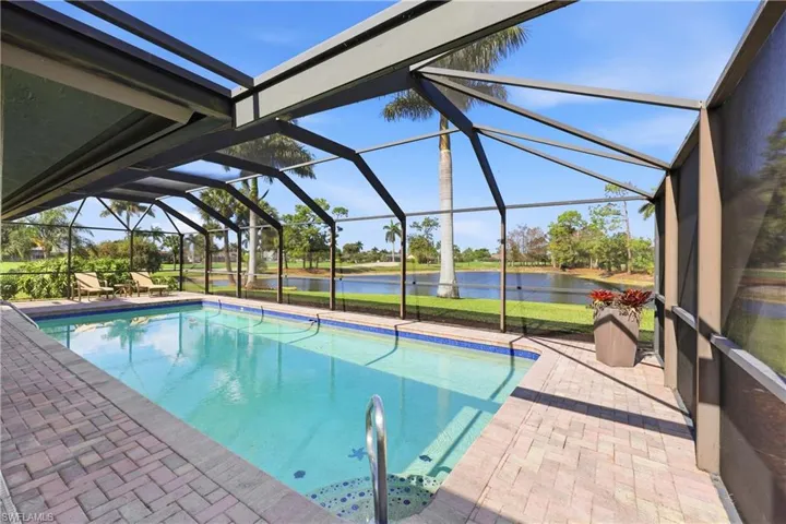 Outdoor pool featuring a sunroom, a patio, a water view.