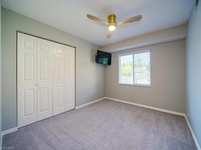 Unfurnished bedroom featuring carpet flooring, a closet, baseboards, and a ceiling fan