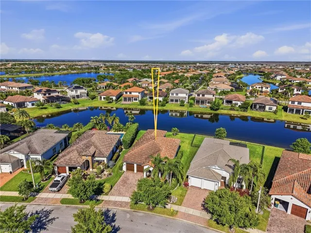 Aerial view of the property, showcasing its tiled roof and the surrounding neighborhood with water features