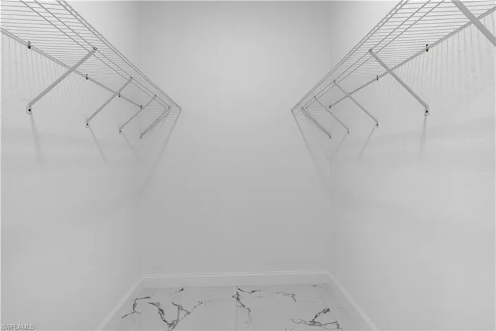 Spacious closet featuring light marble finish floors