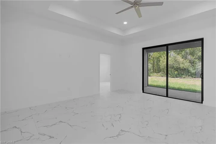 Empty room with light marble finish flooring, a raised ceiling, recessed lighting, and ceiling fan