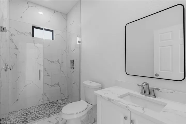 Bathroom with a marble finish shower, vanity, and marble finish floors