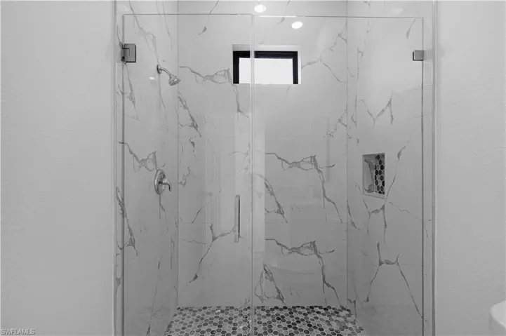 Full bathroom featuring a marble finish shower and a textured wall