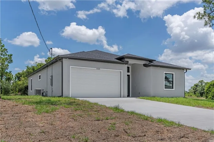View of front facade with stucco siding, concrete driveway, and an attached garage