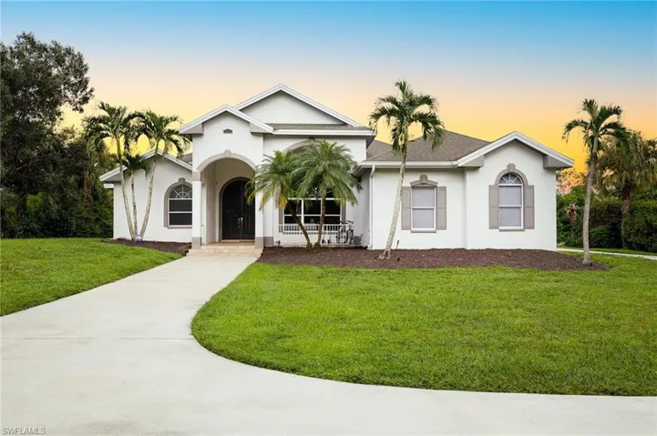 View of front facade featuring a lawn, stucco siding, and a shingled roof