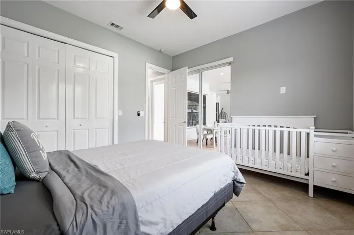 Bedroom featuring a ceiling fan, light tile patterned floors, and a closet
