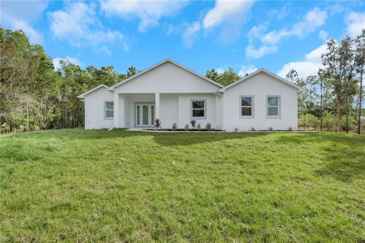 Single story home with a front lawn, stucco siding, french doors, and a porch