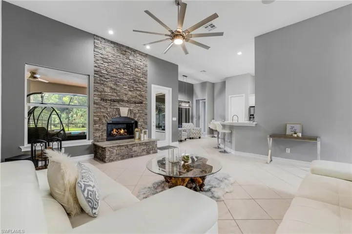 Living room featuring a ceiling fan, light tile patterned floors, a fireplace, a high ceiling, and recessed lighting