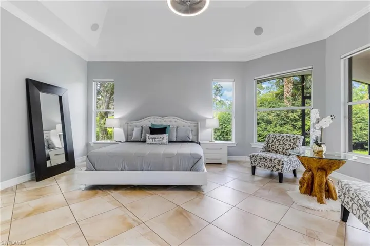 Bedroom with crown molding, a tray ceiling, and light tile patterned floors