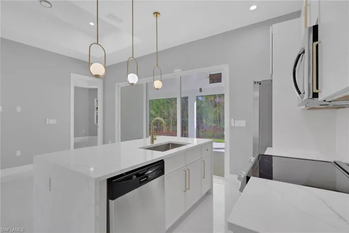 Kitchen featuring white cabinetry, stainless steel appliances, decorative light fixtures, recessed lighting, and light stone countertops