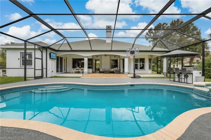 Outdoor pool featuring a sunroom, an outdoor hangout area, a patio, and a lanai