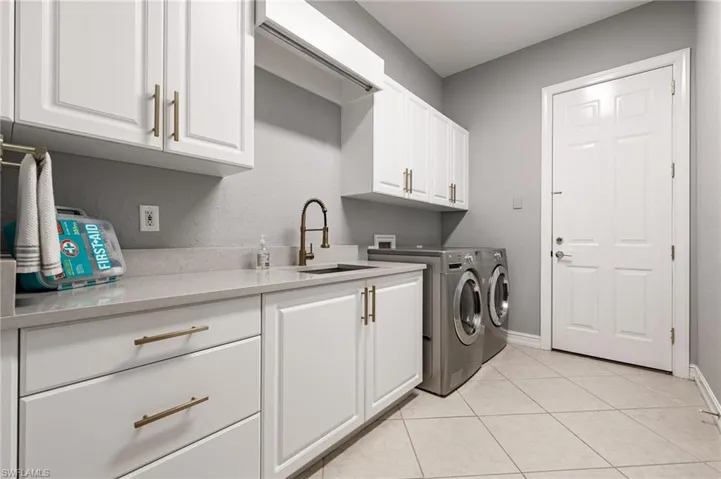 Washroom featuring cabinet space, light tile patterned floors, and independent washer and dryer