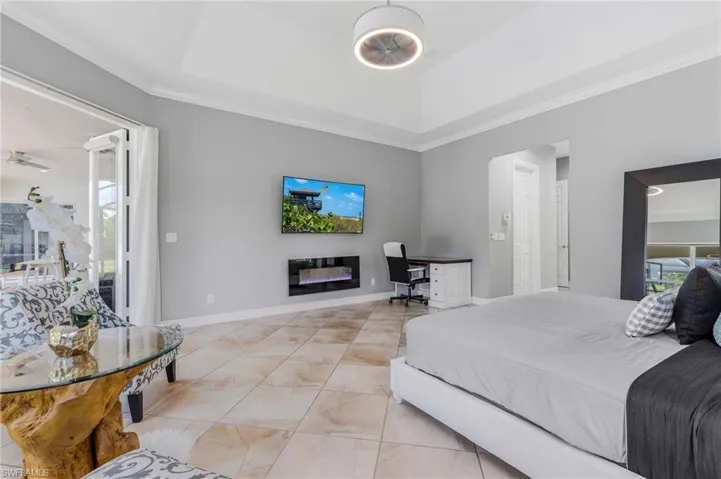 Bedroom featuring multiple windows, a desk, crown molding, a glass covered fireplace, and access to outside