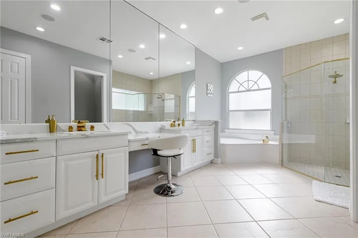 Bathroom featuring a garden tub, a stall shower, vanity, light tile patterned flooring, and healthy amount of natural light