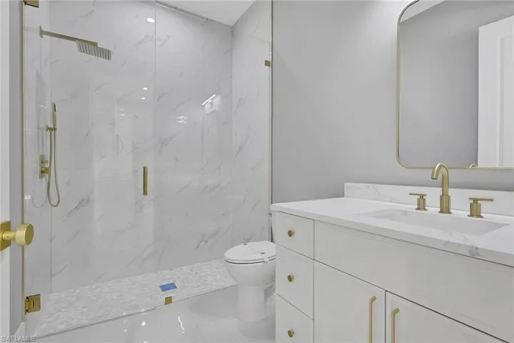 Bathroom featuring vanity and a marble finish shower