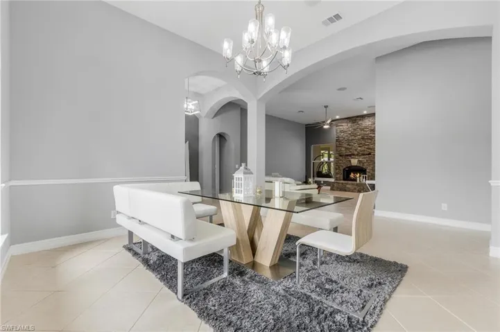 Dining space featuring arched walkways, a fireplace, a chandelier, and light tile patterned floors