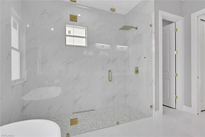 Full bath featuring a marble finish shower and a soaking tub