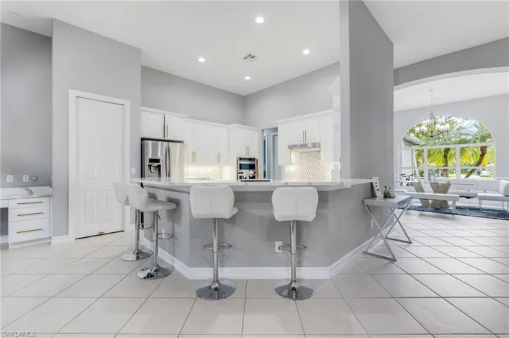 Kitchen featuring a kitchen breakfast bar, white cabinetry, stainless steel refrigerator with ice dispenser, a chandelier, and recessed lighting