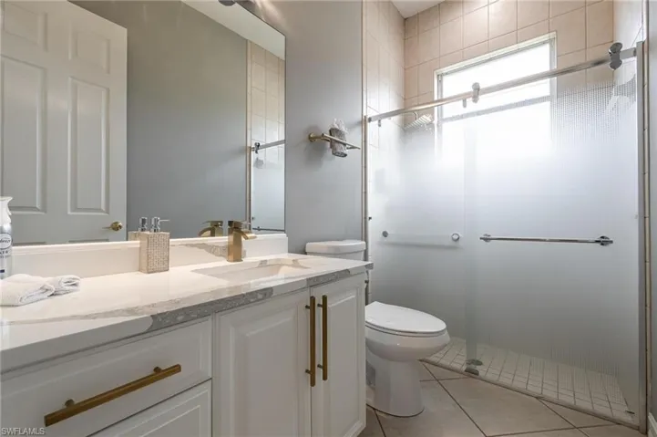 Full bathroom with vanity, light tile patterned floors, and a stall shower