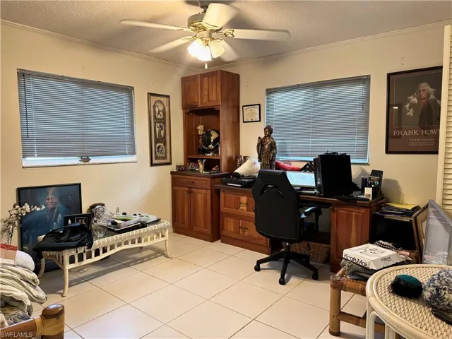 Office with a textured ceiling, a ceiling fan, crown molding, and light tile patterned floors
