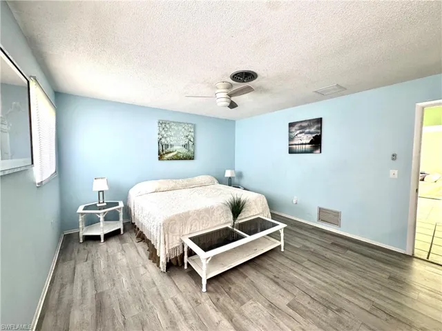 Bedroom with a textured ceiling, wood finished floors, and a ceiling fan