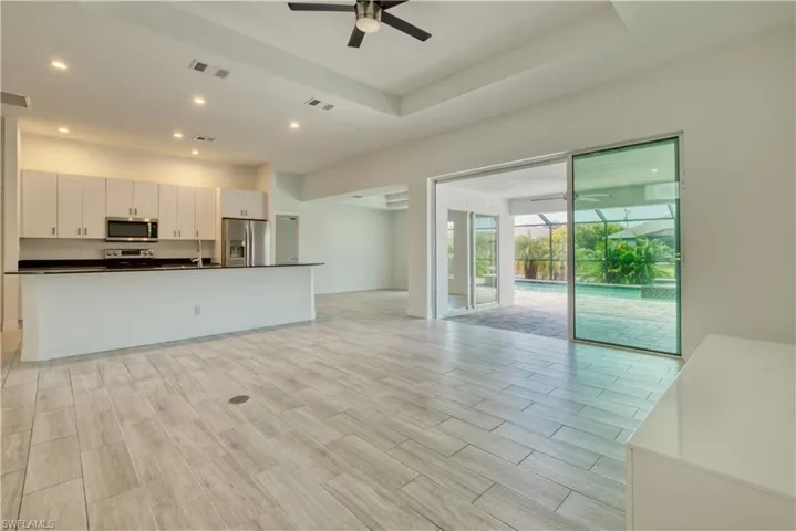 Unfurnished living room with ceiling fan, wood finish floors, a sunroom, recessed lighting, and a raised ceiling