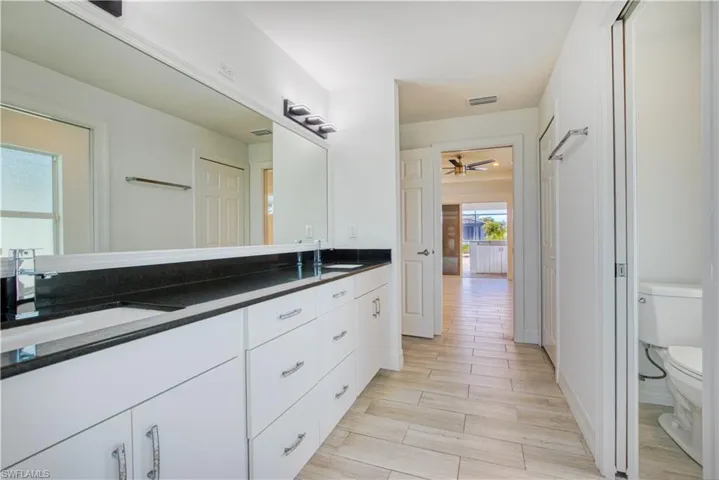 Bathroom featuring double vanity, wood finish floors, and a ceiling fan