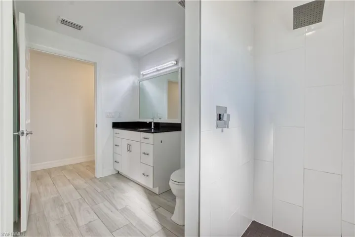 Bathroom featuring vanity, a tile shower, and wood tiled floors
