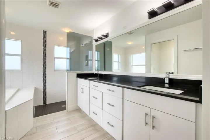 Bathroom featuring double vanity, walk in shower, and wood tiled floors