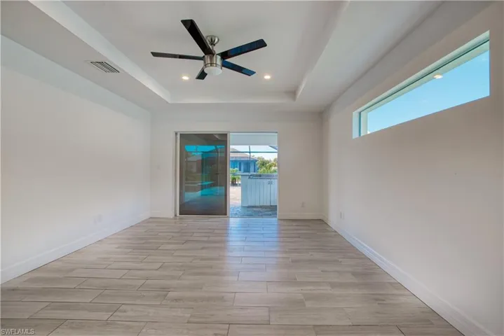 Spare room featuring wood tiled floors, ceiling fan, a tray ceiling, and recessed lighting