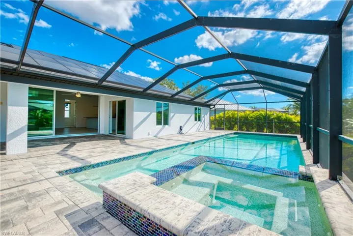 Integrated pool / hot tub featuring a sunroom, a patio area, and glass enclosure