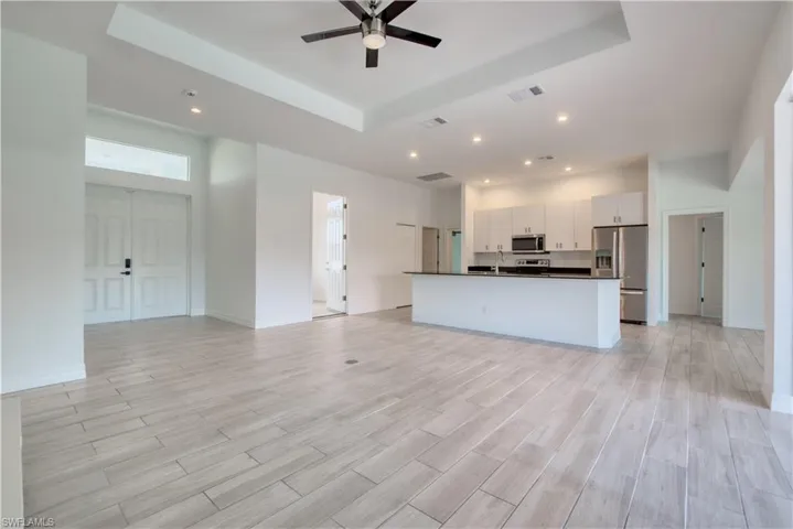 Unfurnished living room featuring a tray ceiling, a ceiling fan, wood tiled floors, and recessed lighting