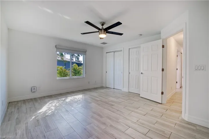 Unfurnished bedroom featuring two closets, wood finish floors, and a ceiling fan