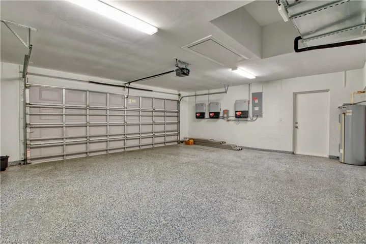 Garage with water heater, electric panel, and a garage door opener