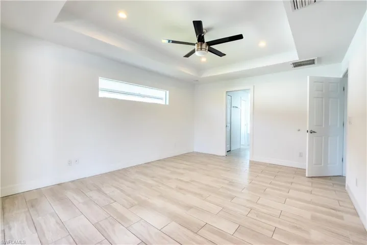 Unfurnished bedroom featuring wood finish floors, a ceiling fan, recessed lighting, and a raised ceiling