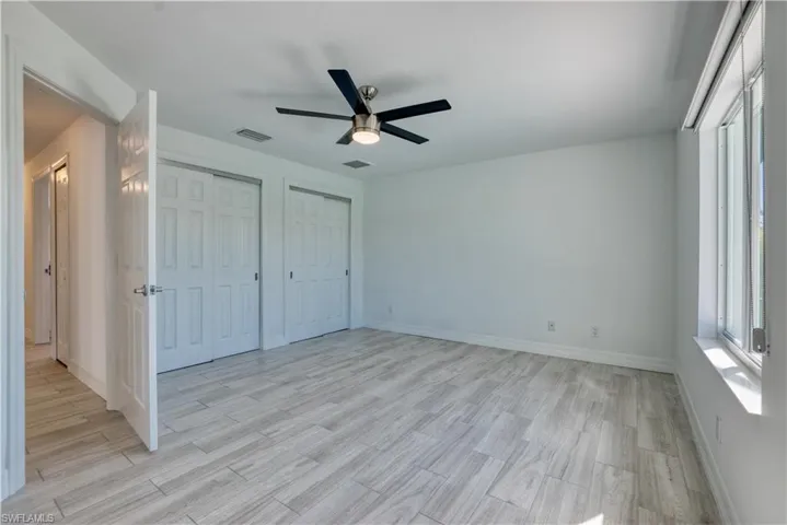 Unfurnished bedroom with two closets, a ceiling fan, and light wood-style floors