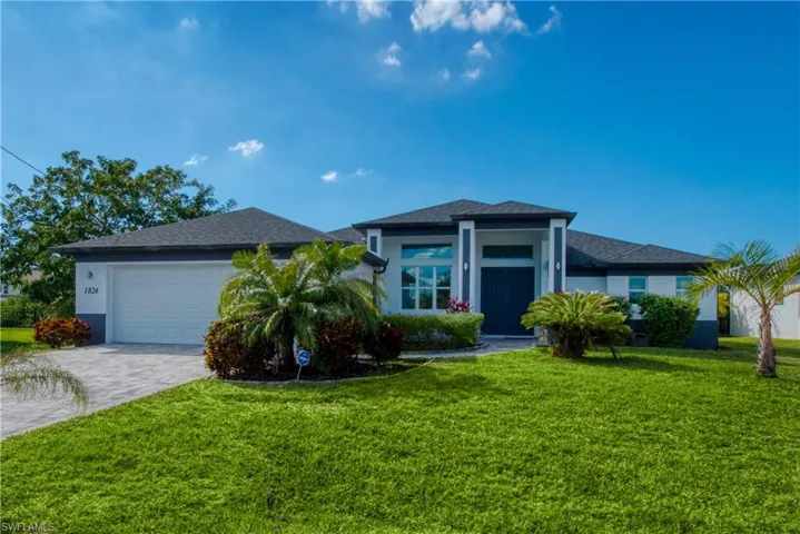 Prairie-style home with a front yard, decorative driveway, stucco siding, an attached garage, and a shingled roof