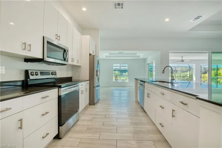 Kitchen with stainless steel appliances, white cabinetry, recessed lighting, dark stone counters, and wood finish floors