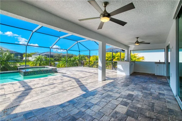 View of patio featuring a pool with connected hot tub, a sunroom, a ceiling fan, and glass enclosure