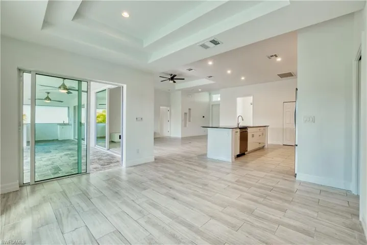 Unfurnished living room with a tray ceiling, ceiling fan, recessed lighting, and wood finish floors