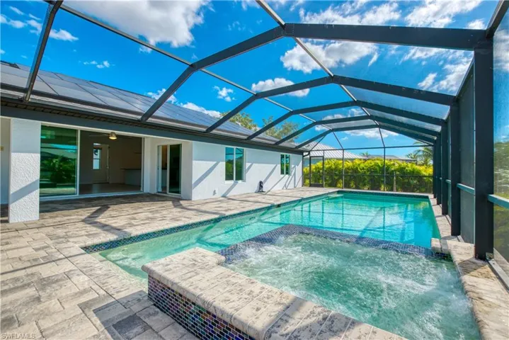 Integrated pool / hot tub with a sunroom, a patio, and a lanai