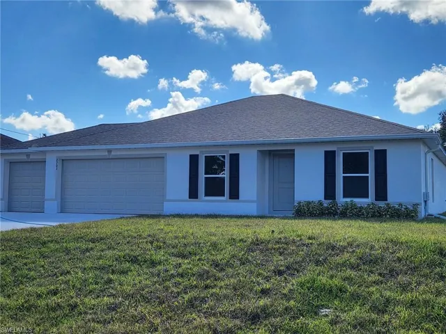 Ranch-style home with stucco siding, a front lawn, a garage, and concrete driveway