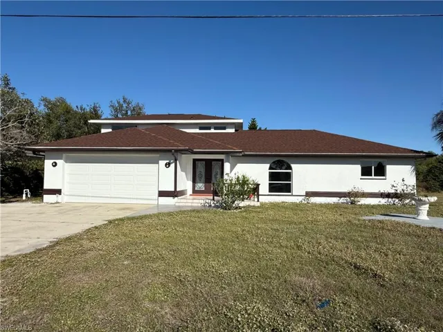 View of front of home featuring stucco siding, an attached garage, concrete driveway, and a front yard