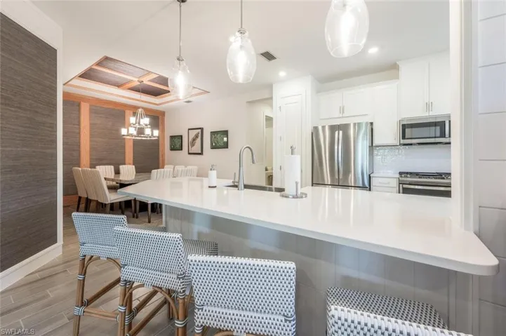 Kitchen with pendant lighting, sink, white cabinetry, a kitchen breakfast bar, and stainless steel appliances