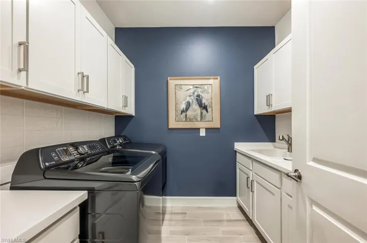 Washroom with cabinets, washing machine and clothes dryer, and sink
