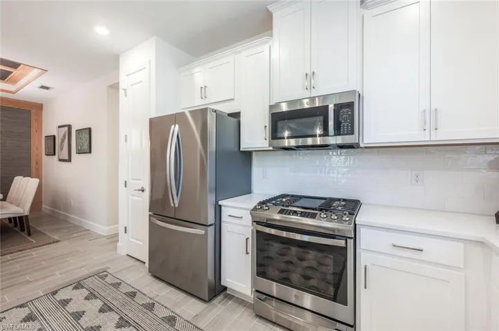 Kitchen with stainless steel appliances, white cabinetry, and tasteful backsplash