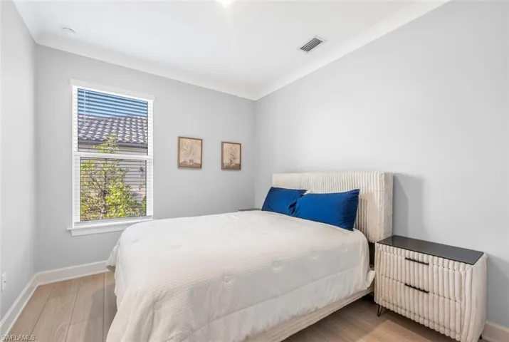 Bedroom featuring light wood-type flooring and ornamental molding