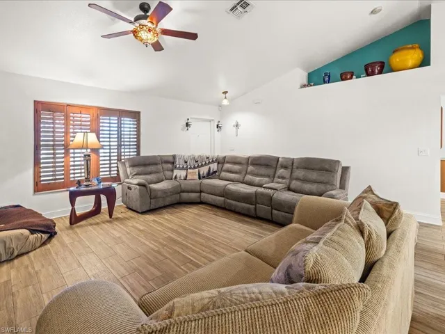Living room featuring lofted ceiling, a ceiling fan, and wood tiled floors