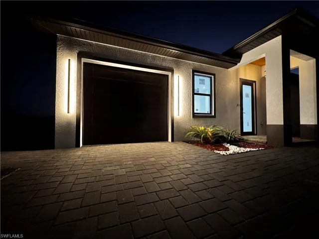 View of front of property featuring stucco siding, decorative driveway, and a garage
