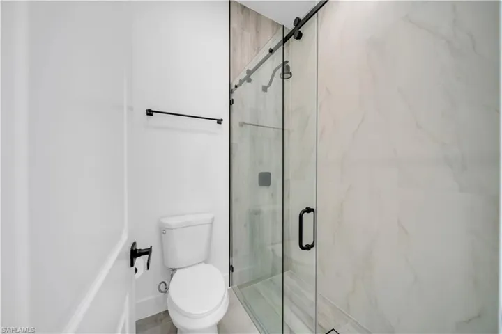 Bathroom featuring toilet and a marble finish shower